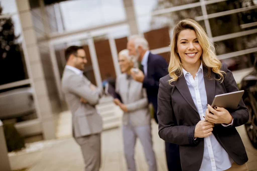 Profissional de contabilidade se atualizando sobre a NBC PG 12 R4 de educação continuada do CFC, com colegas ao fundo