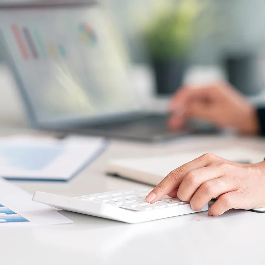 Profissional analisando dados fiscais em calculadora e notebook durante treinamento prático sobre a Reforma Tributária 2025 na Escola Superior