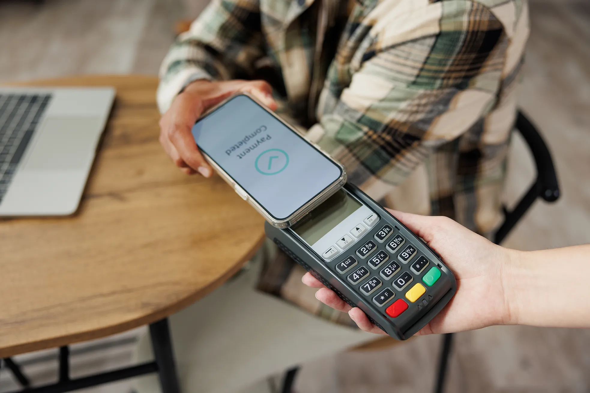 Pessoa realizando pagamento por aproximação com smartphone em maquininha de cartão, representando MEIs usando maquininha e obrigatoriedade da EFD-Reinf em 2025