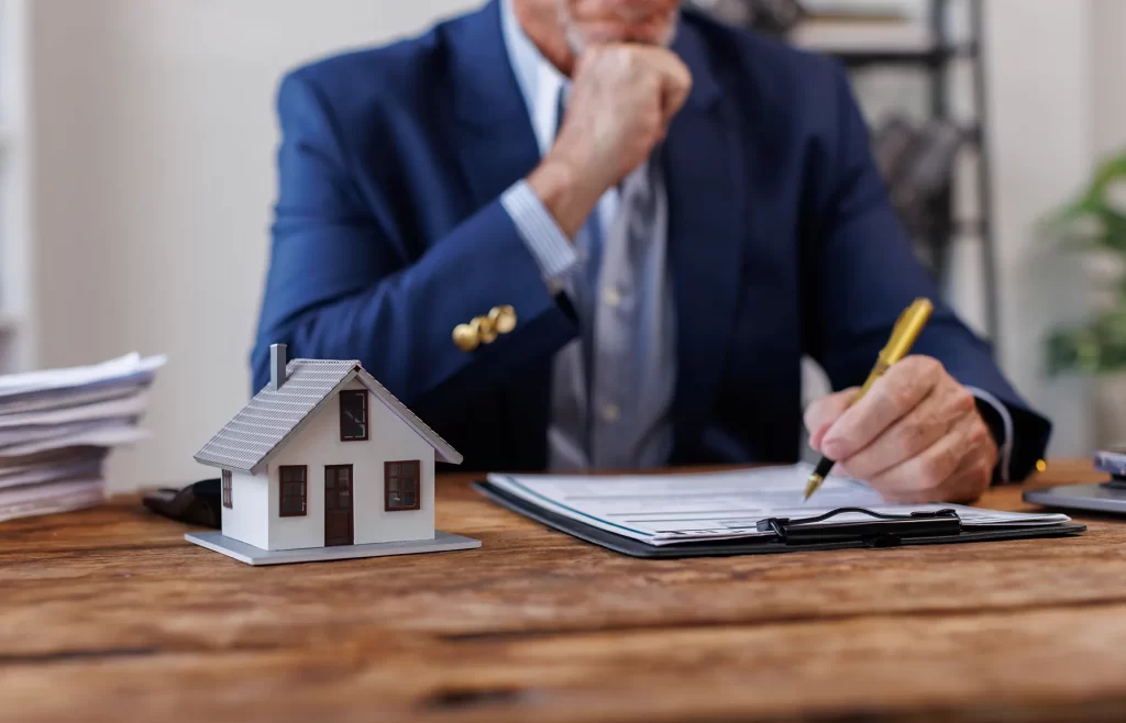 Homem analisando documentos de aluguel com miniatura de casa na mesa para cálculo de IRRF na EFD-Reinf 2025
