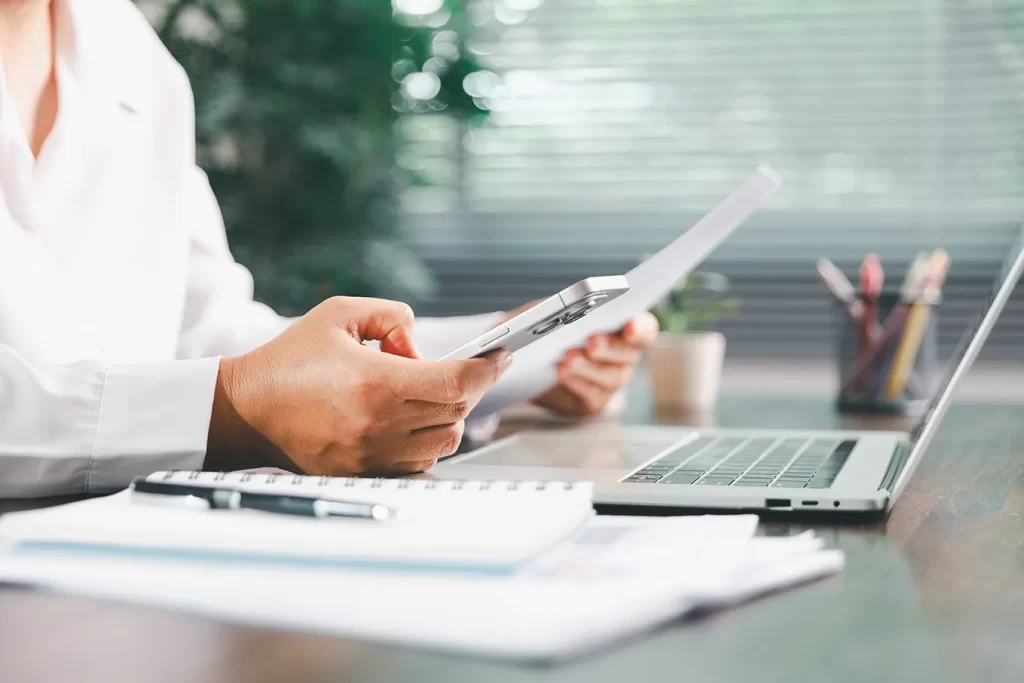 Profissional analisa documentos imobiliários no notebook e celular — estratégias com IBS e CBS na Reforma Tributária 2025