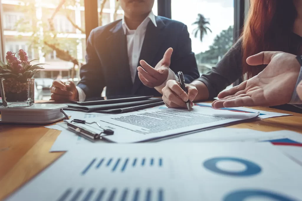 Profissionais analisando e assinando relatórios com gráficos — IFRS 18/CPC 51 e nova estrutura da Demonstração de Resultado.