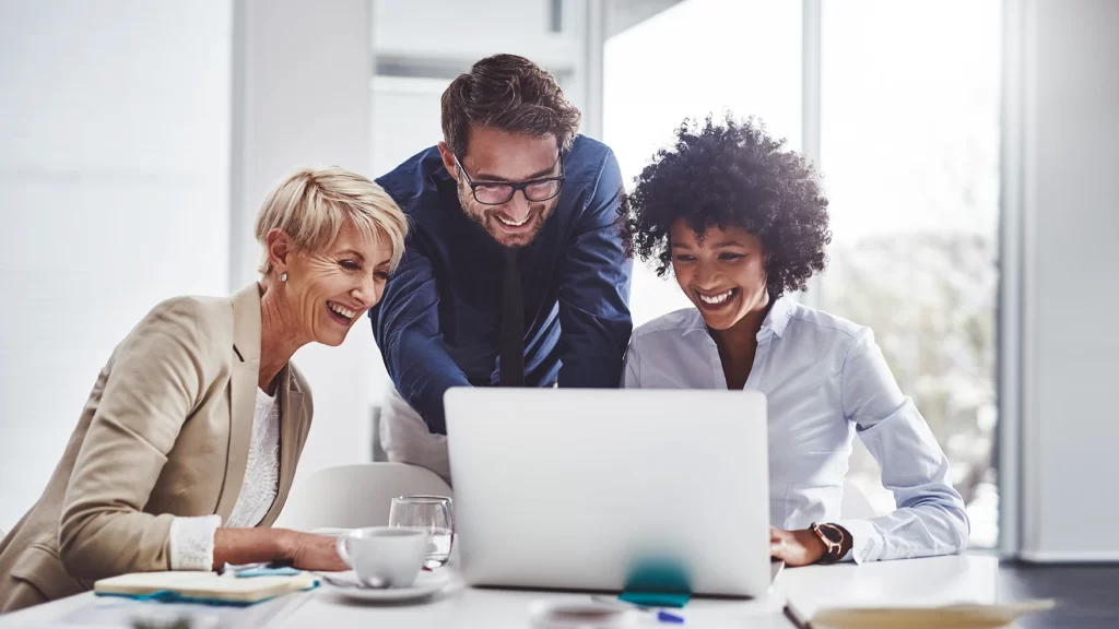 Equipe contábil analisando DRE no notebook durante reunião em escritório.