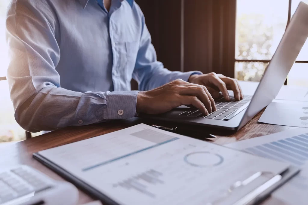 Profissional de finanças analisando relatórios e digitando em notebook, representando a aplicação da IFRS 9 e os impactos da reforma tributária de 2025