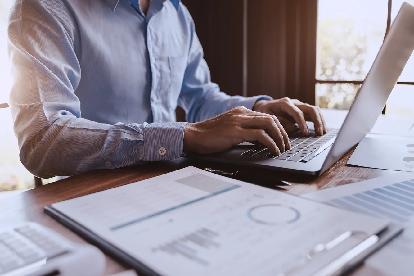 Profissional de finanças analisando relatórios e digitando em notebook, representando a aplicação da IFRS 9 e os impactos da reforma tributária de 2025