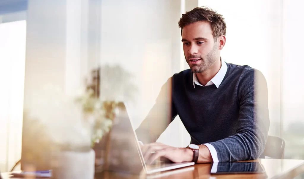 Profissional analisando relatórios no notebook, em contexto de MPMs e divulgação no IFRS 18.