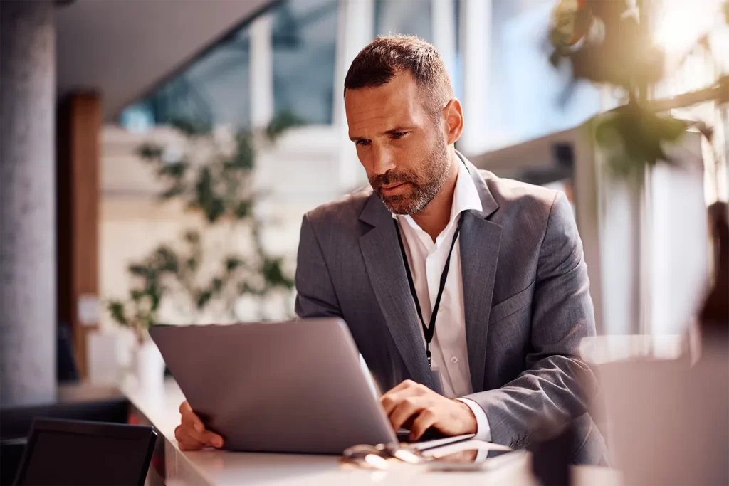 Profissional analisando documentos no laptop em escritório, representando o custo das obrigações acessórias no Lucro Real.