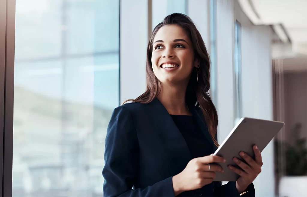Profissional sorrindo em ambiente corporativo segurando um tablet, representando a escolha do regime tributário e como evitar erros