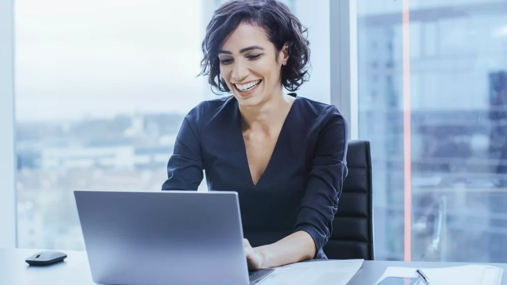 Profissional contábil sorrindo ao trabalhar com compensação de prejuízos fiscais no computador