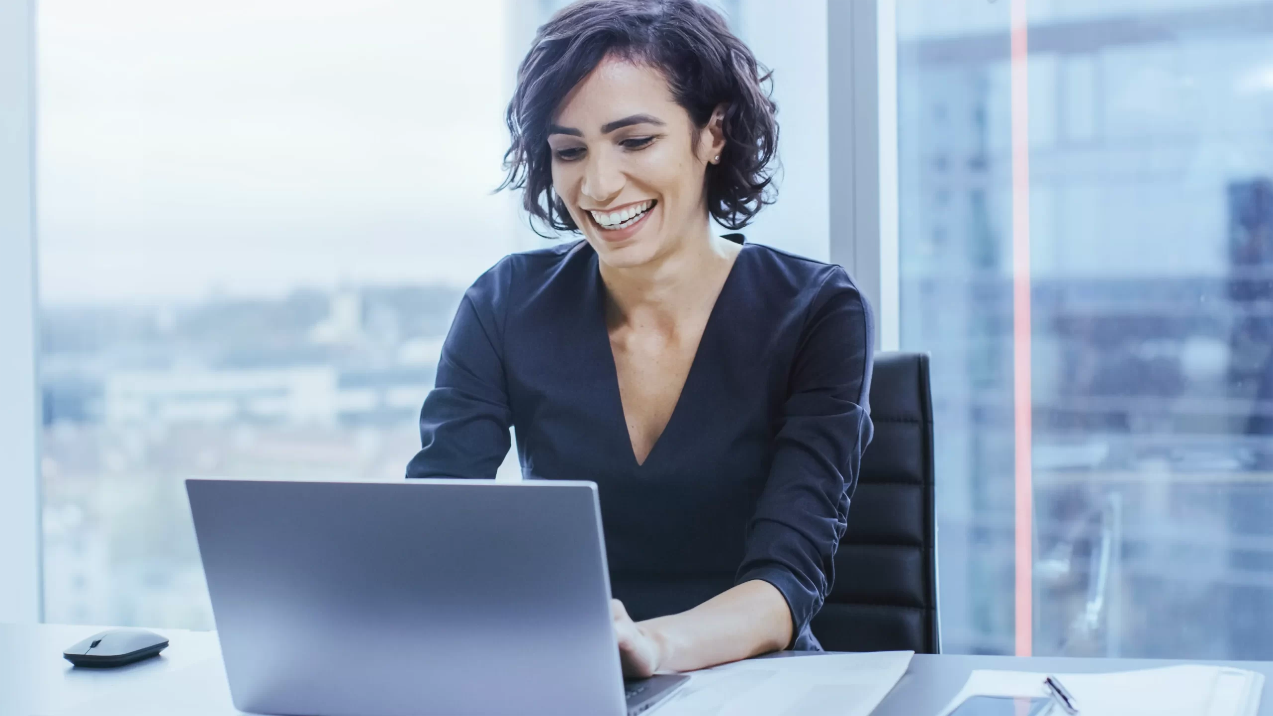 Profissional contábil sorrindo ao trabalhar com compensação de prejuízos fiscais no computador