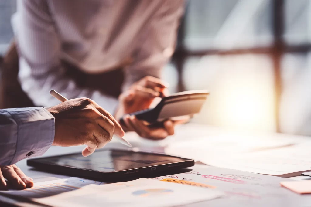 Profissional analisando dados financeiros em tablet e calculadora para escolha entre Lucro Real e Lucro Presumido