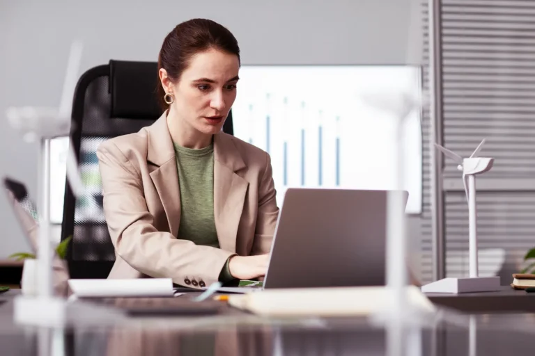 Profissional em ambiente corporativo analisando dados no computador, em contexto de riscos psicossociais e obrigações fiscais