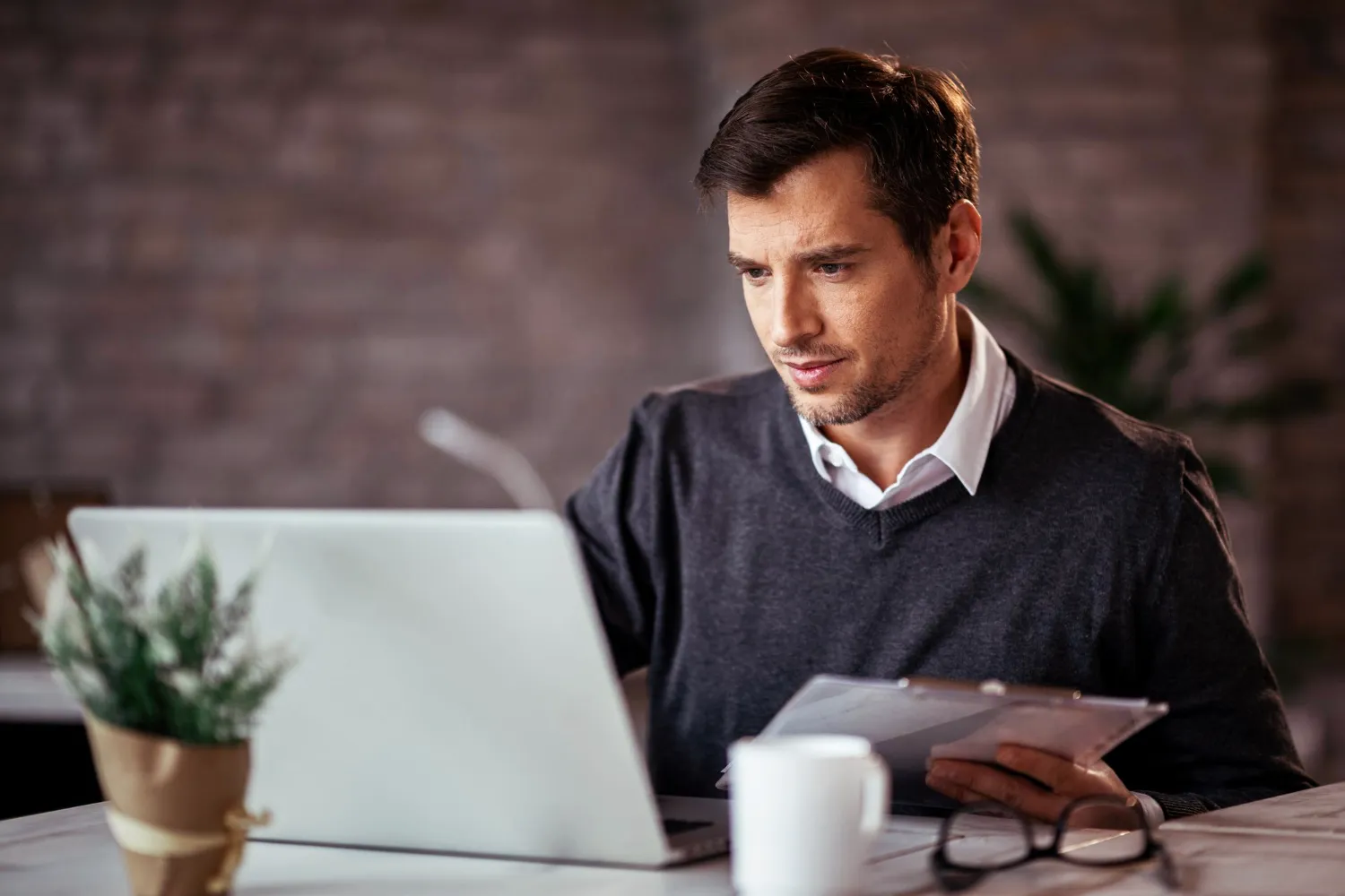 Profissional analisando documentos no notebook em contexto de DCTF Web 2026 e obrigações acessórias