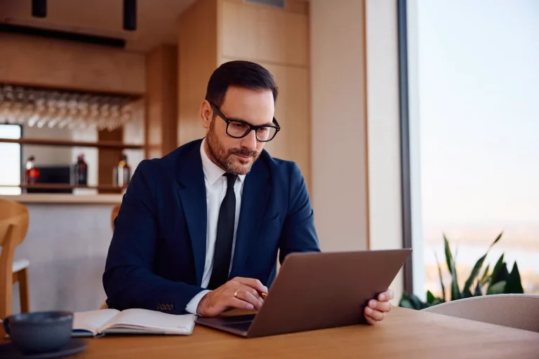 Consultor tributário analisando documentos fiscais no laptop para adaptação da NF-e ao IBS, CBS e Split Payment em 2026