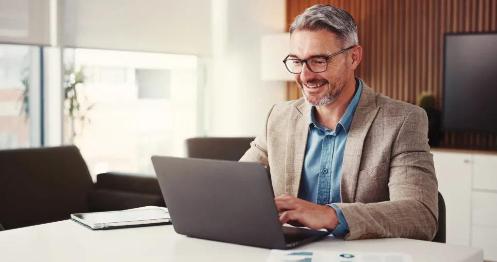 Homem analisando informações no notebook sobre as mudanças de PIS, IPI, ICMS e ISS na Reforma Tributária