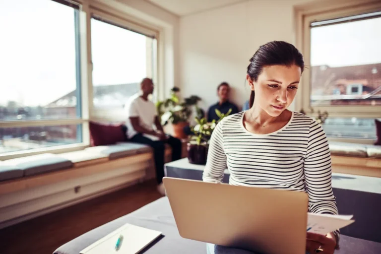 Profissional de contabilidade confere no notebook e em um relatório impresso a contabilização de uma permuta imobiliária